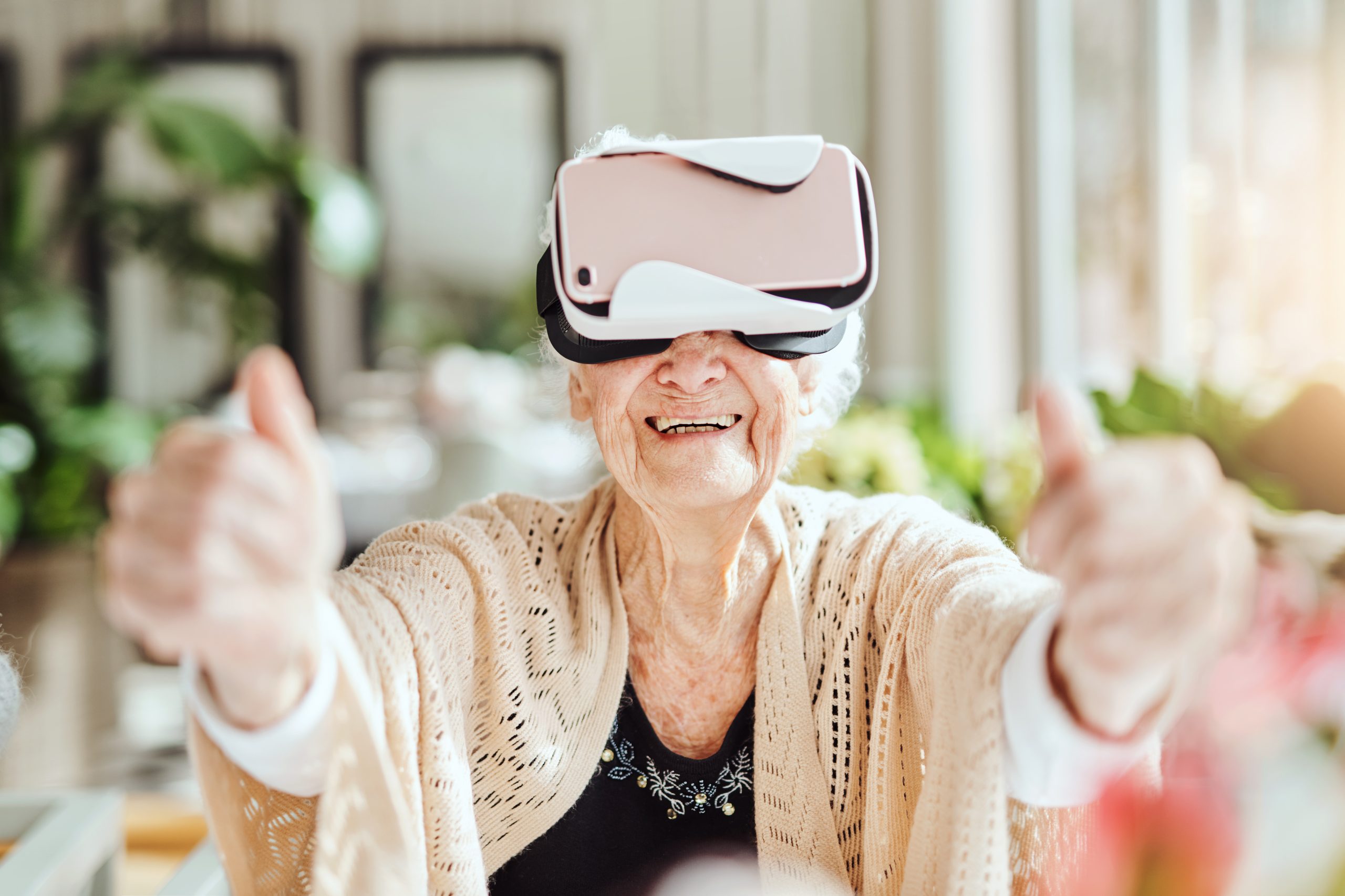 Een oude vrouw met een VR-bril op die twee duimen opsteekt.